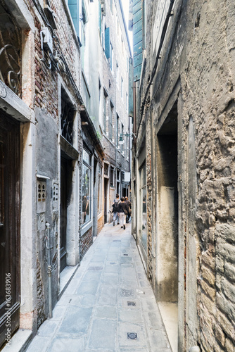 Narrow cobblestone alley in the oldest part of Venice  called  De Regina   with people walking  Italy