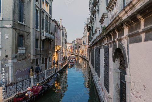 Channel called "Rio Marin" and anchorage called "Garzotti" at dusk with people walking and gondolas in Venice, Italy