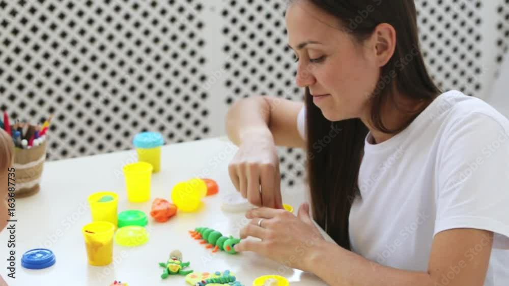 Young attractive mother with little cute daughter play with modeling clay Young attractive mother with little cute daughter play with modeling clay