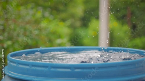 Drops of water from the roof fall into a blue barrel