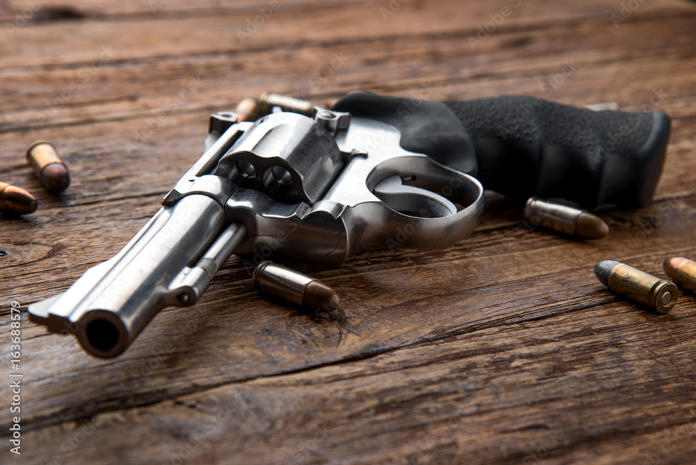 Obraz premium Gun with ammunition on wooden background.