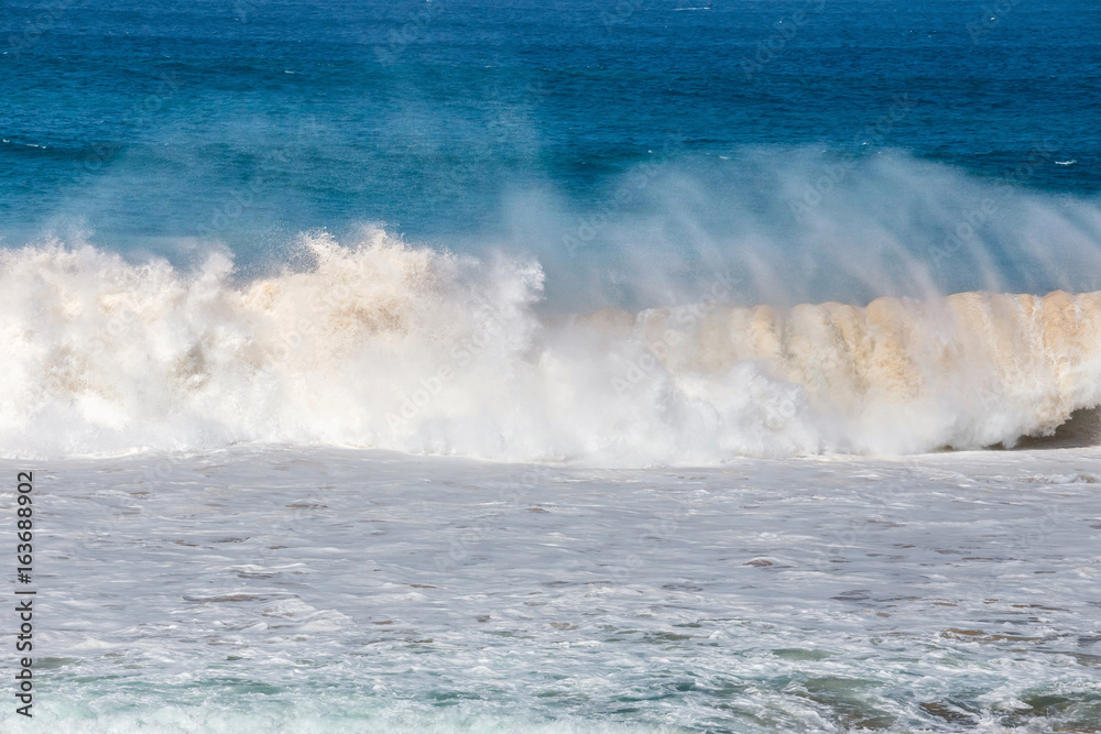 blue wave crashes down at the beach in El Cotillo village in Fuerteventura island, Spain