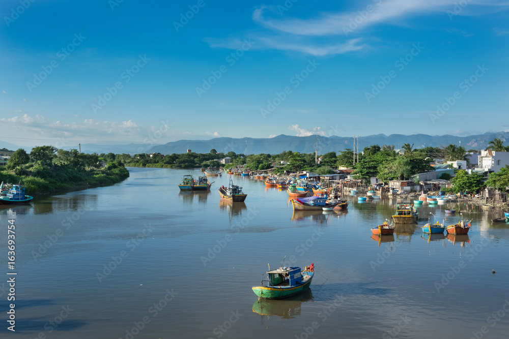 Vietnam in the morning. Traditional Vietnamese boats, fishing boats on the river, cloudy blue sky.