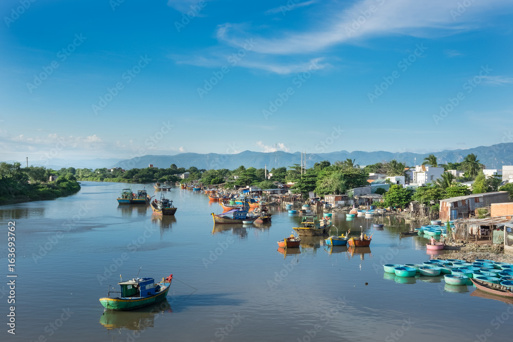 Vietnam in the morning. Traditional Vietnamese boats, fishing boats on the river, cloudy blue sky.