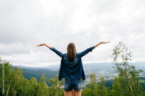 Woman in wild nature asking sky for blessing and enjoying nature greatness. Relaxation, meditation, harmony of inner life and mind. Unity of human and world. Exaltation of heart and consciousness.