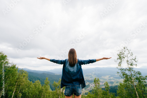 Woman in wild nature asking sky for blessing and enjoying nature greatness. Relaxation, meditation, harmony of inner life and mind. Unity of human and world. Exaltation of heart and consciousness.