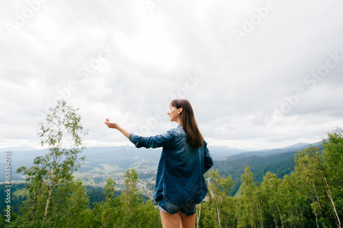 Woman in wild nature asking sky for blessing and enjoying nature greatness. Relaxation, meditation, harmony of inner life and mind. Unity of human and world. Exaltation of heart and consciousness.