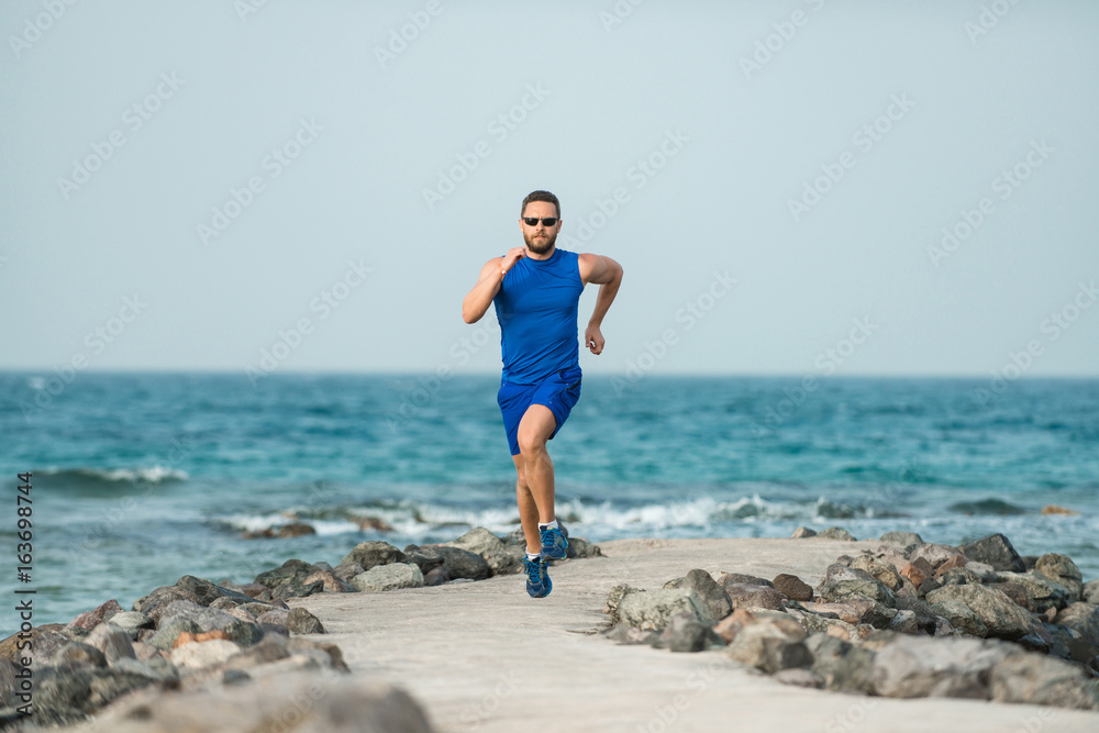 Running man jogging on beach
