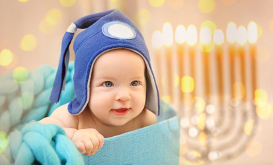 Adorable baby in funny hat sitting in box with turquoise knitted plaid, close up