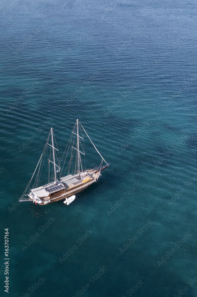 Aerial view of a little yacht on amazing beach with a turquoise and transparent sea. Emerald Coast, Sardinia, Italy. Aerial view of a little yacht on amazing beach with a turquoise and transparent sea. Emerald Coast, Sardinia, Italy.