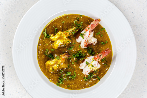 Prawn curry on white plate served with parsley