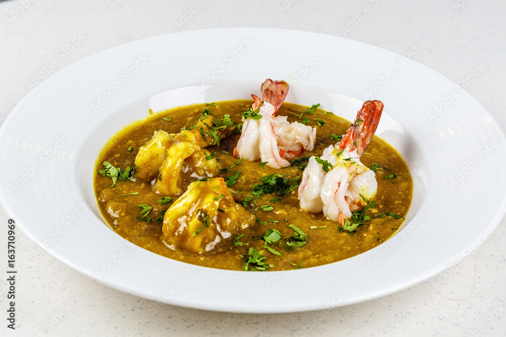 Prawn curry on white plate served with parsley Prawn curry on white plate served with parsley