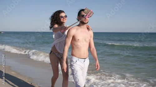 love couple make Selfi photo on beach, guy circling girl, positive young people shoot video from holiday travel, Selfphoto couple on vacation near ocean coast, mobil photo