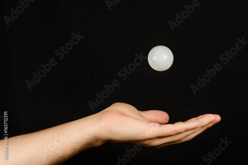 Men's hand which catches the white plastic ball isolated on black background