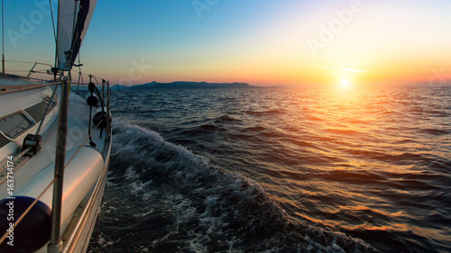 Sunset from the deck of the sailing boat moving in a sea.