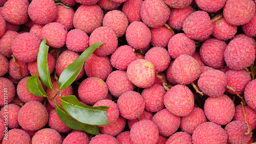 Lychee, Fresh lychee and peeled showing the red skin and white flesh with green leaf .