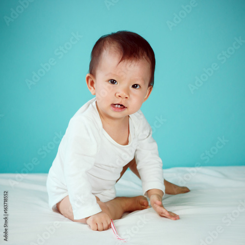 A crawling baby in diaper with blue background (soft focus on the eyes)