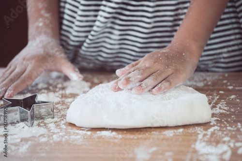 Little child girl hands kneading dough prepare for baking cookies in vintage color tone