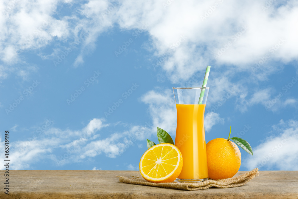 Glass of fresh orange juice on wooden table, Fresh fruits Orange juice in glass with group on blue sky background with copy Space for your text. Glass of fresh orange juice on wooden table, Fresh fruits Orange juice in glass with group on blue sky background with copy Space for your text.