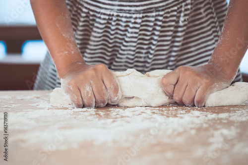 Little child girl hands kneading dough prepare for baking cookies in vintage color tone