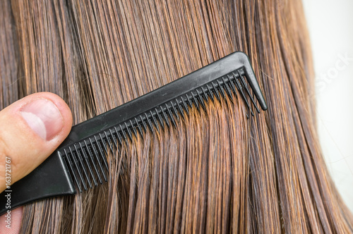 Close-up of dark wet hair with a comb - hair care concept photo