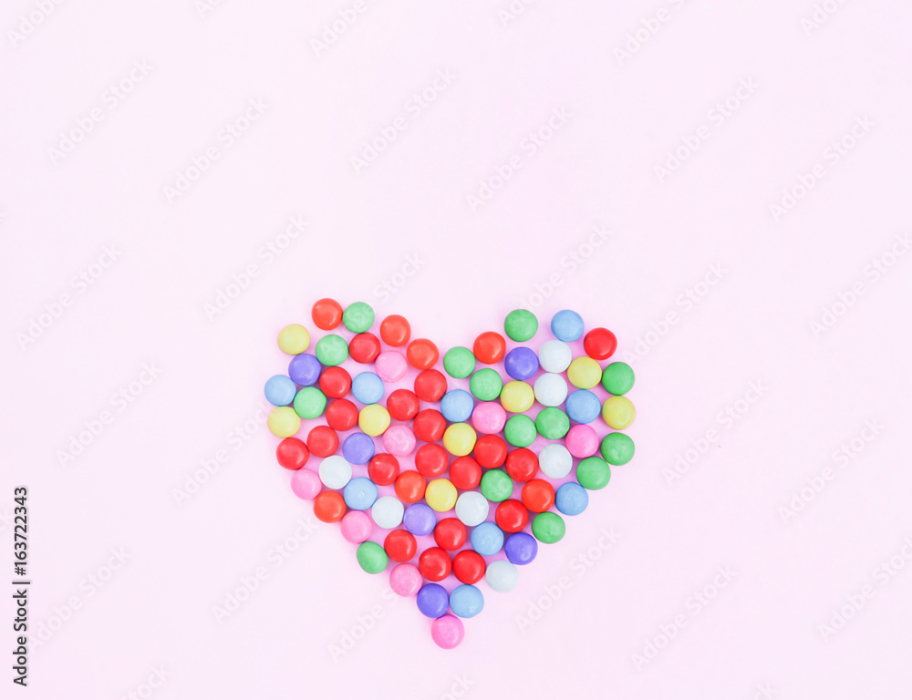 Colorful candies heart shape on pink
