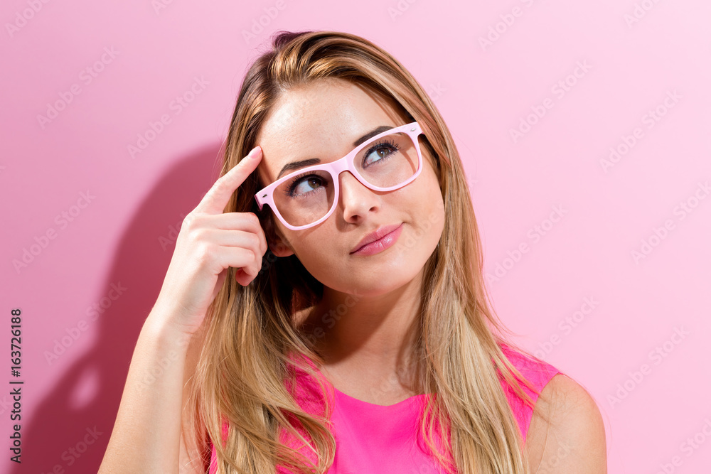 Young woman in a thoughtful pose on a pink background Young woman in a thoughtful pose on a pink background