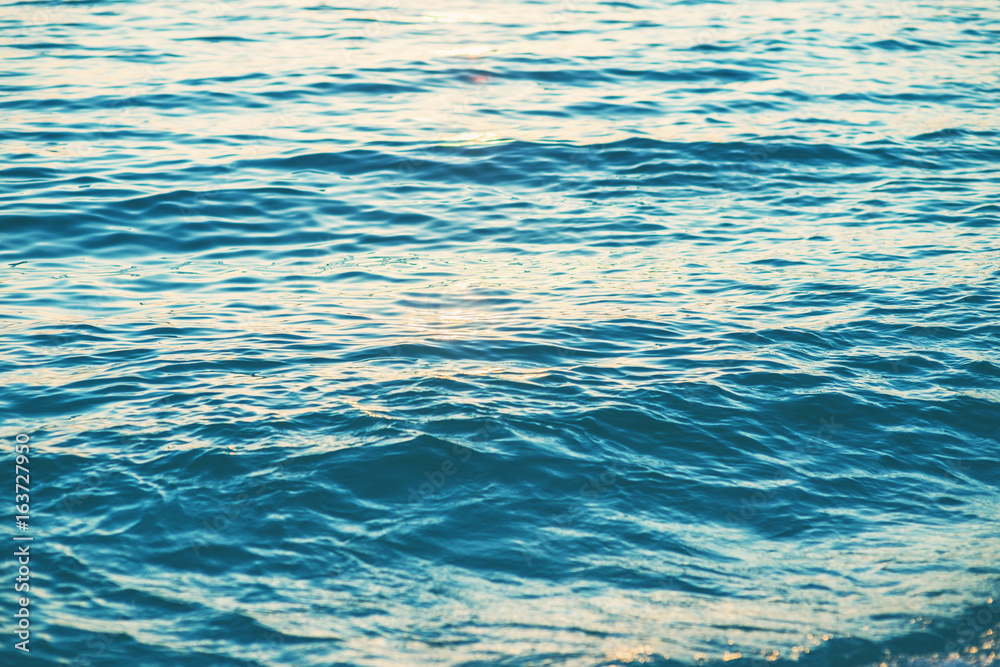 Naklejka premium Sea waves and ripples at sunset background