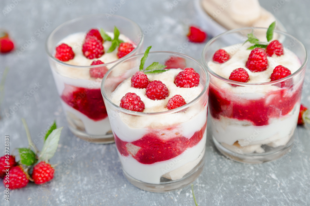 Tiramisu with raspberry in glasses on grey background. Three portion. Italian dessert Tiramisu with raspberry in glasses on grey background. Three portion. Italian dessert