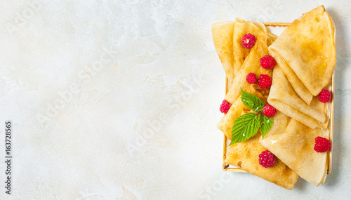 Homemade pancakes with honey, raspberries with powder sugar. Flat lay, top view. copy space photo