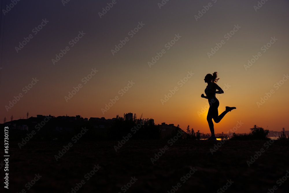 The woman does exercises at sunrise.