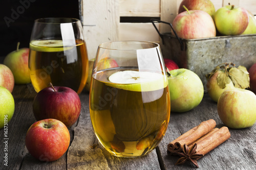 Apple juice in glass with cinnamon and anisetree on a dark wooden background