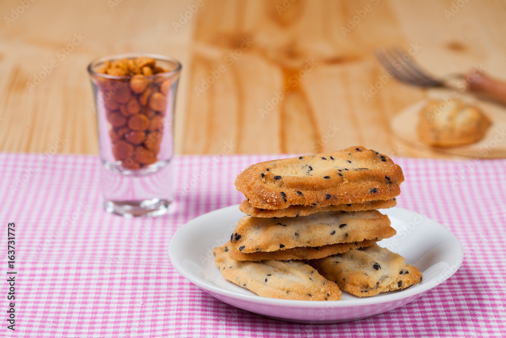 Home made a small sweet cookie with black sesame, typically round, flat, and crisp.Cookie in dish on tablecloth. Home made a small sweet cookie with black sesame, typically round, flat, and crisp.Cookie in dish on tablecloth.