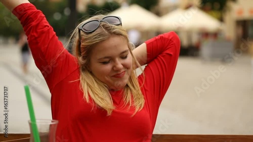 Pretty girl in red shirt sitting in the restaurant and yawning
