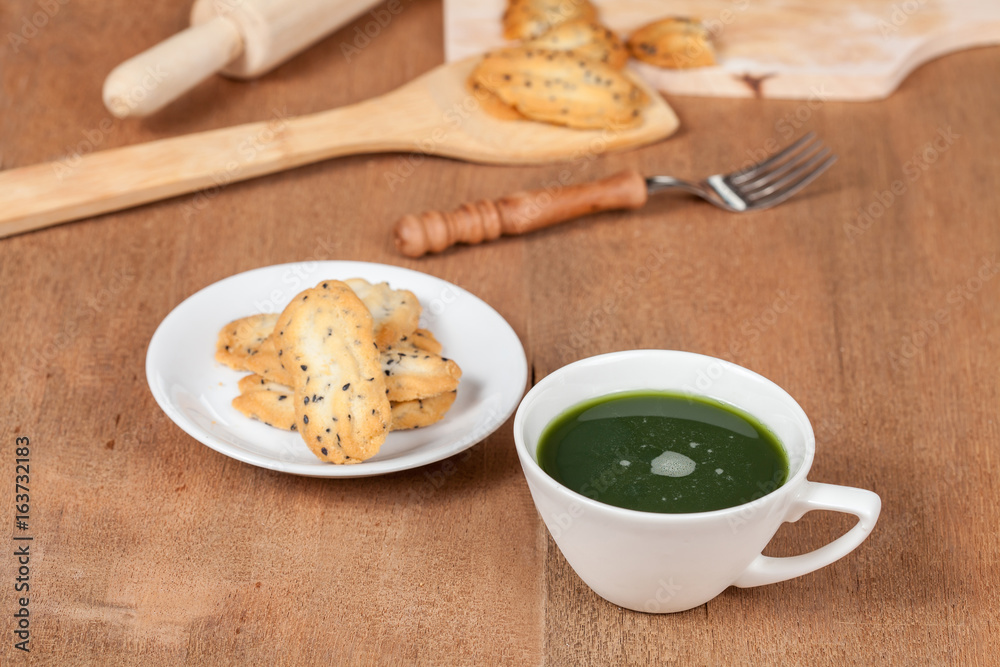 Hot and fresh green tea on wood with home made a small sweet cookie with black sesame. Hot and fresh green tea on wood with home made a small sweet cookie with black sesame.