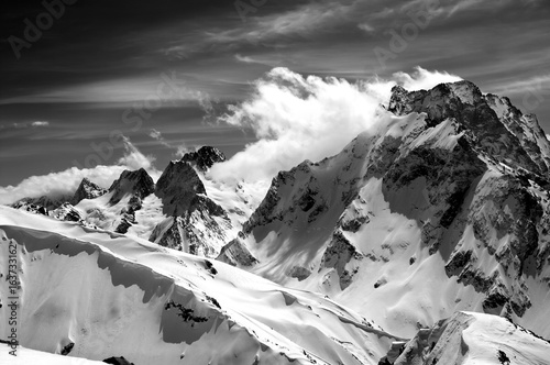 Schilderij op canvas Black and white winter mountains with snow cornice and cloudy sky in nice sun da