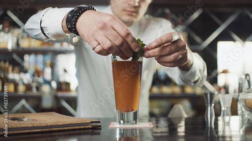 Bartender in hat is preparing cocktail in bar