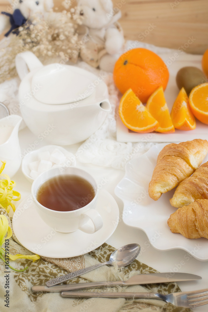 Continental breakfast with gold french croissants fruits and cup of tea on white table in a Morning light. Breakfast concept Continental breakfast with gold french croissants fruits and cup of tea on white table in a Morning light. Breakfast concept