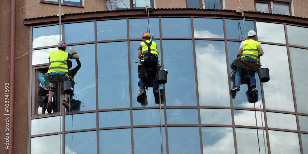 Alpinists spider-men wash the windows of high building point-of-sale-entertaining to the center