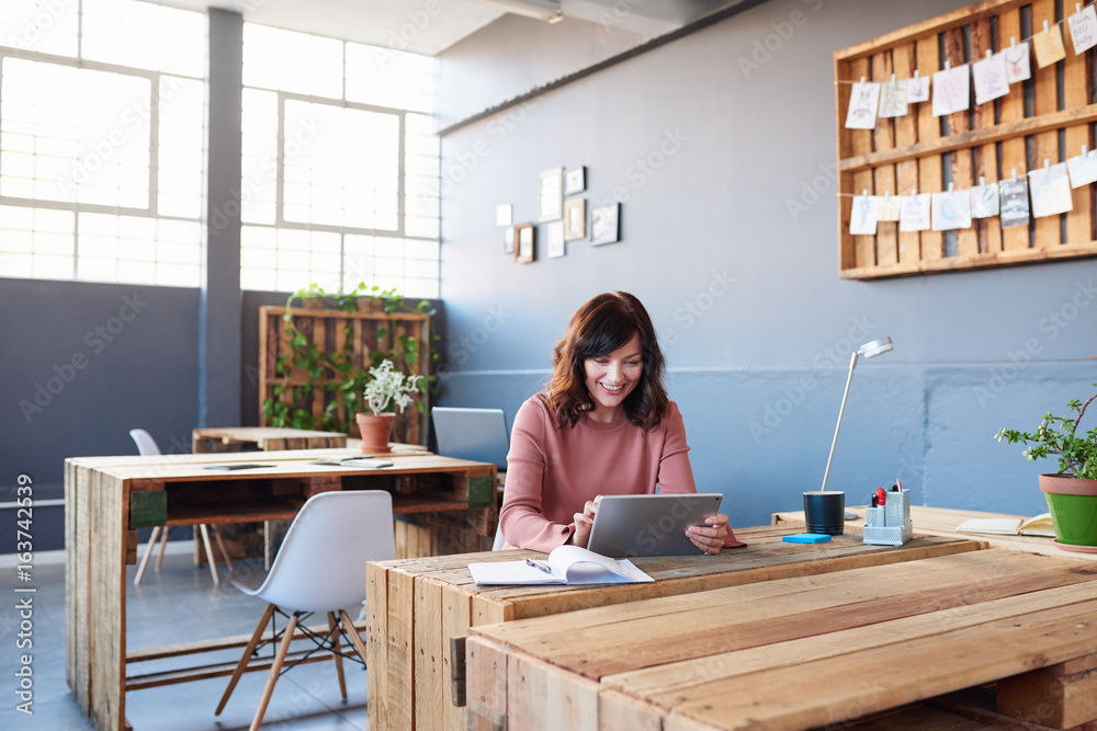 Smiling young businesswoman working on a tablet in an office Smiling young businesswoman working on a tablet in an office