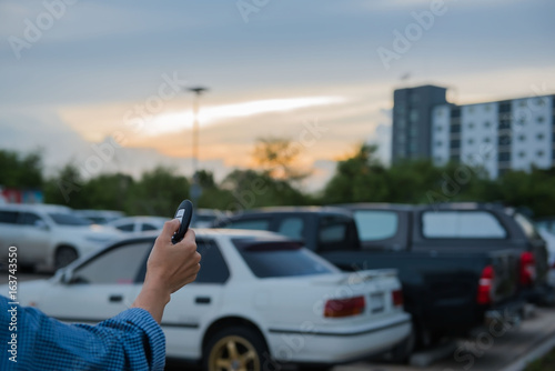 remote control key Car in hand In the outdoor parking lot at evening , system automatic. 