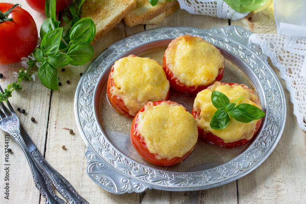 Stuffed tomatoes. Tomatoes baked with cheese and chicken on a wooden kitchen table.