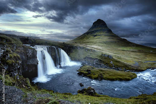 Cloudy overcast day of the Kirkjufellsfoss Waterfall with Kirkjufell mountain in the background in Iceland. Long exposure.