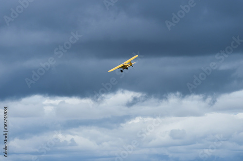 Yellow plane flying over Masai Mara looking for poachers, with blue cloudy sky in background, masai mara, Kenya, Africa
