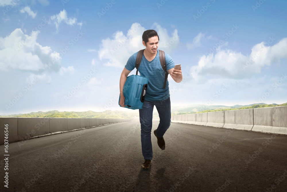 Young asian tourist running with holding phone and suitcase Young asian tourist running with holding phone and suitcase