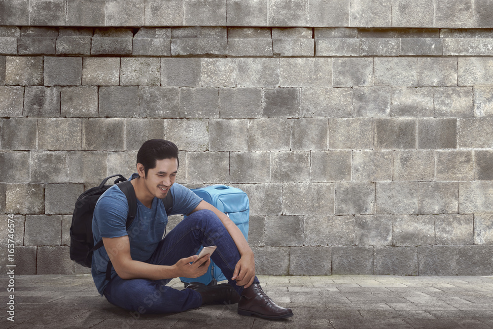 Handsome asian backpacker with phone resting Handsome asian backpacker with phone resting