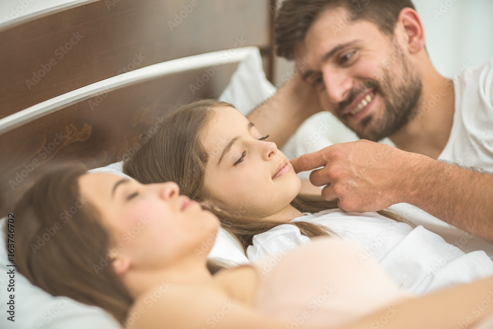 The little girl sleeping near the parents in the bed The little girl sleeping near the parents in the bed