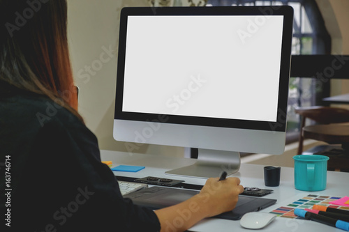 Side view of an artist drawing something on graphic tablet at the office. Blank screen monitor for graphic display montage.