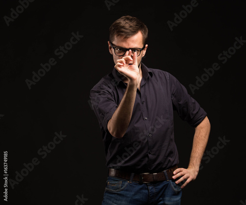 Young pensive man portrait of a confident businessman showing by hands placard black background. Ideal for banners, registration forms, presentation, landings, presenting concept.