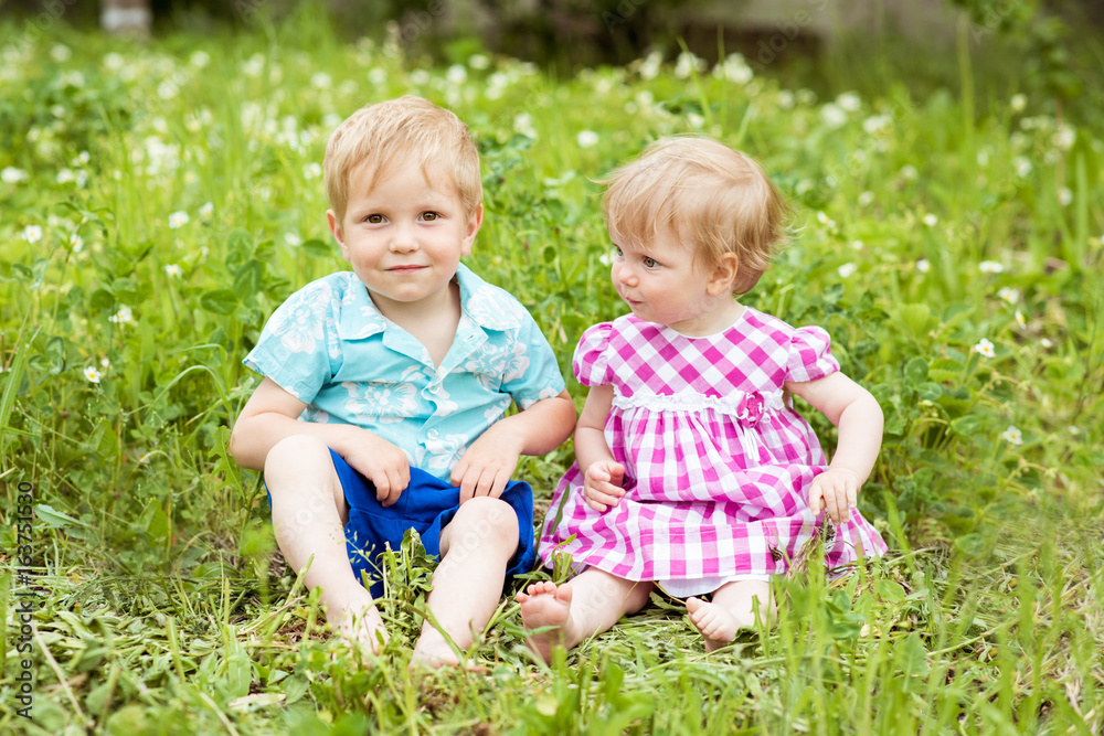Boy and girl together. Children on a green lawn Boy and girl together. Children on a green lawn